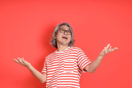 The senior Asian man with casual clothes standing on the orange background.の写真素材