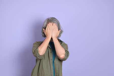 The senior Asian man with casual clothes standing on the purple background.の写真素材