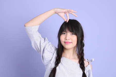 The young Asian girl in purple preppy dressed standing on the purple background.