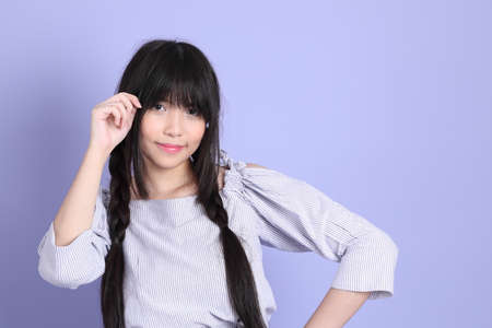 The young Asian girl in purple preppy dressed standing on the purple background.の写真素材