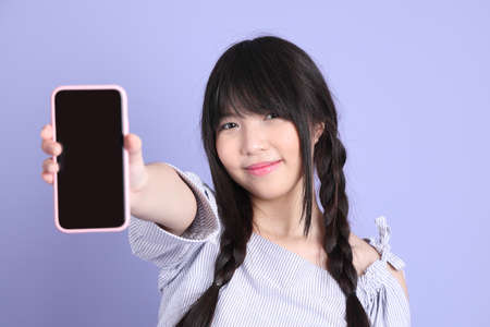 The young Asian girl in purple preppy dressed standing on the purple background.