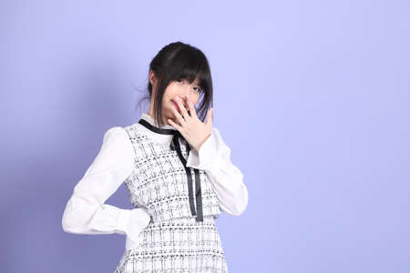 The young Asian girl in white preppy dressed standing on the purple background.の写真素材