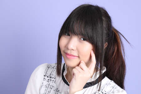 The young Asian girl in white preppy dressed standing on the purple background.