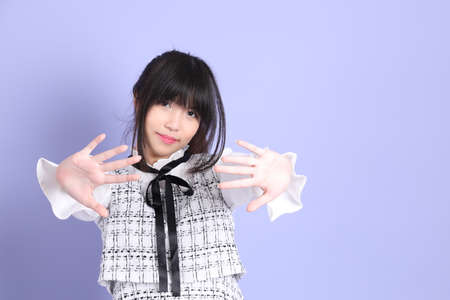 The young Asian girl in white preppy dressed standing on the purple background.の写真素材