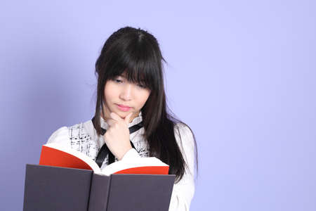 The young Asian girl in white preppy dressed standing on the purple background.
