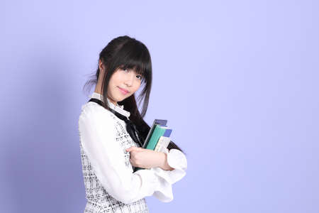 The young Asian girl in white preppy dressed standing on the purple background.の写真素材
