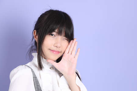 The cute young Asian girl with white preppy dressed style standing on the purple backgroundの写真素材