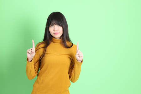 The cute young Asian girl with casual dressed standing on the green backgroundの写真素材