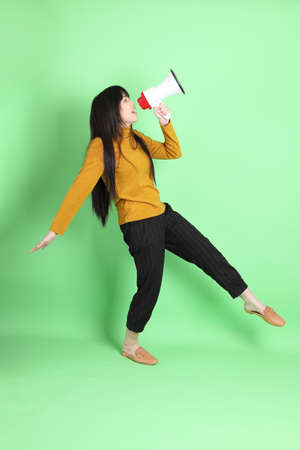 The cute young Asian girl with casual dressed standing on the green backgroundの写真素材