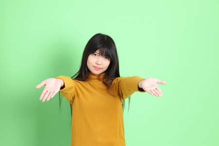 The cute young Asian girl with casual dressed standing on the green backgroundの写真素材