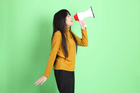 The cute young Asian girl with casual dressed standing on the green background