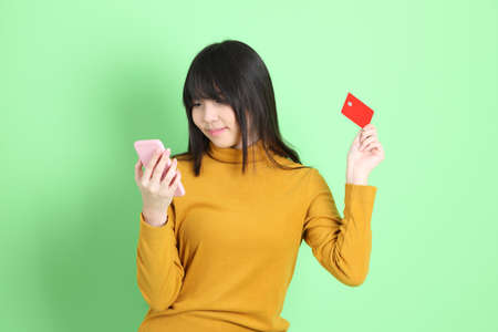 The cute young Asian girl with casual dressed standing on the green backgroundの写真素材