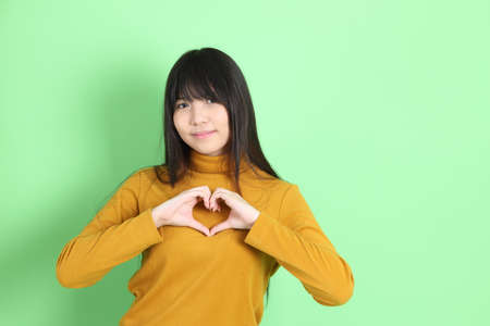 The cute young Asian girl with casual dressed standing on the green backgroundの写真素材