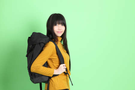 The cute young Asian girl with casual dressed standing on the green backgroundの写真素材
