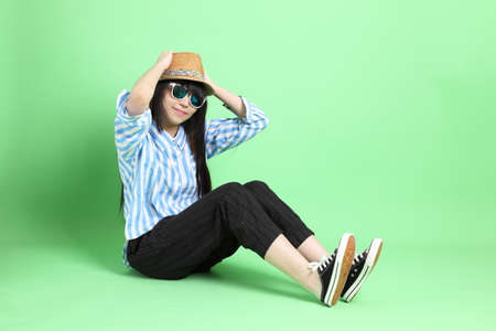 The young Asian girl in casual dressed sitting on the green background.の写真素材