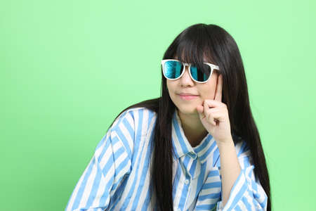 The young Asian girl in casual dressed sitting on the green background.の写真素材