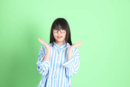 The young Asian girl in casual dressed standing on the green background.の写真素材