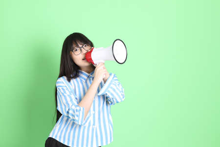 The cute young Asian girl with casual dressed standing on the green backgroundの写真素材