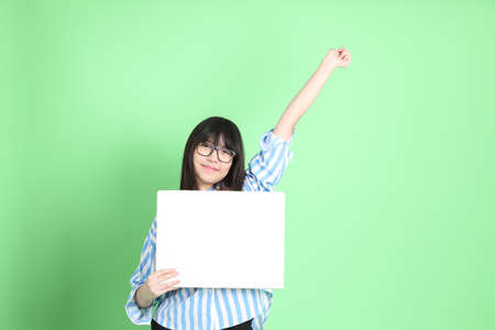 The cute young Asian girl with casual dressed standing on the green backgroundの写真素材