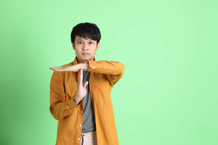 The young adult Asian man with smart casual clothes standing on the light green background.