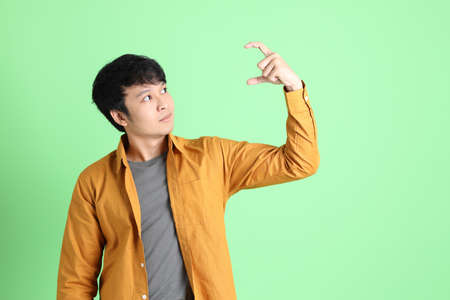 The young adult Asian man with smart casual clothes standing on the light green background.の写真素材