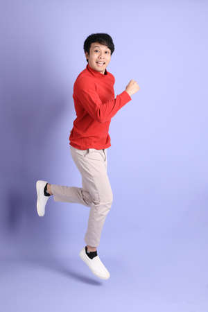 The young adult southeast Asian man with red long sleeve shirt standing on the light green...