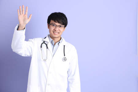 The young adult Asian physician standing on the purple background.の写真素材