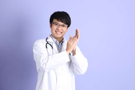 The young adult Asian physician standing on the purple background.の写真素材