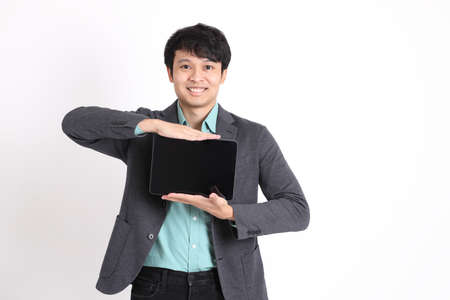 The young adult businessman standing on the white background.の写真素材