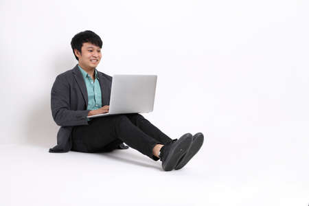 The young adult businessman sitting on the white background.の写真素材