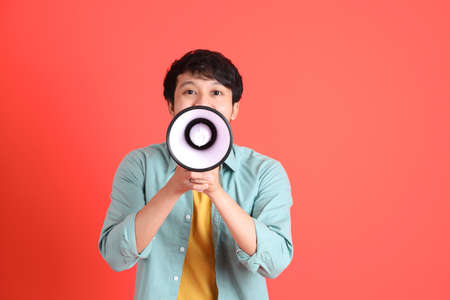 The young adult southeast Asian man with green shirt standing on the orange background.の写真素材