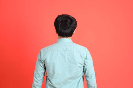 The young adult southeast Asian man with green shirt standing on the orange background.の写真素材