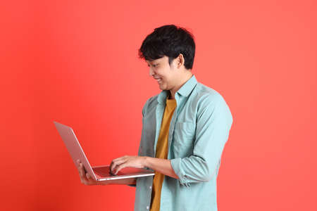 The young adult southeast Asian man with green shirt standing on the orange background.の写真素材