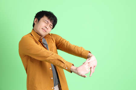 The young adult Asian man with smart casual clothes standing on the light green background.