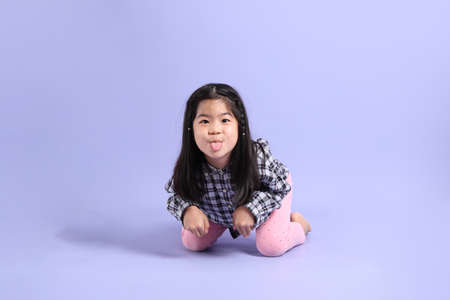 The young Asian gril sitting on the purple background.