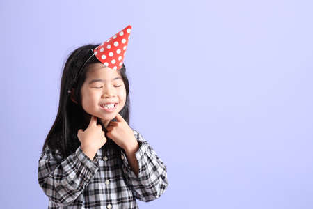 The young Asian gril standing on the purple background.の写真素材