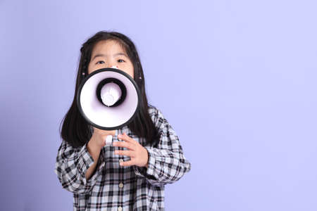 The young Asian gril standing on the purple background.