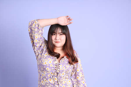 The chubby Asian woman standing on the purple background with the casual clothes.の写真素材