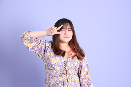 The chubby Asian woman standing on the purple background with the casual clothes.の写真素材