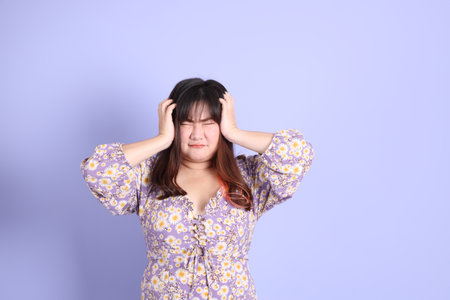 The chubby Asian woman standing on the purple background with the casual clothes.の写真素材