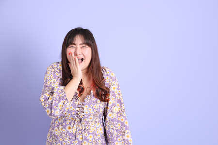 The chubby Asian woman standing on the purple background with the casual clothes.の写真素材