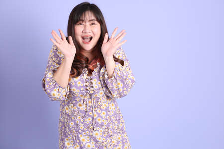 The chubby Asian woman standing on the purple background with the casual clothes.の写真素材