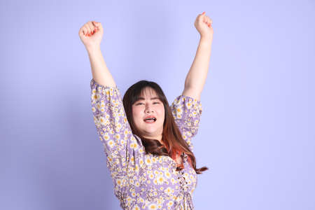 The chubby Asian woman standing on the purple background with the casual clothes.の写真素材