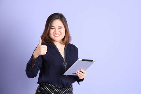 The chubby Asian woman standing on the purple background with the casual clothes.の写真素材