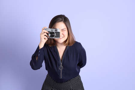 The chubby Asian woman standing on the purple background with the casual clothes.