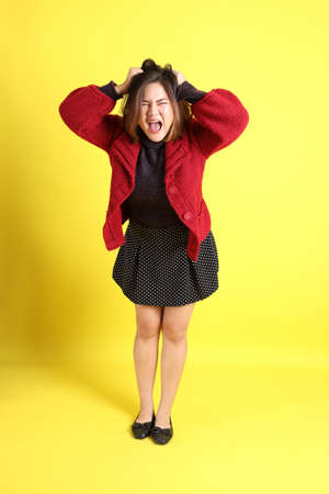 The chubby Asian woman standing on the yellow background with the casual clothes.