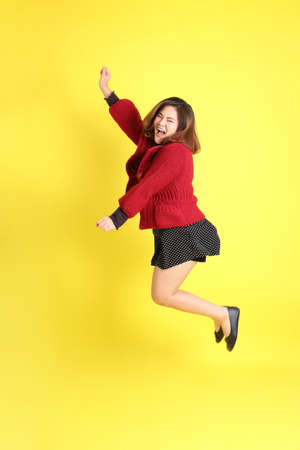 The chubby Asian woman standing on the yellow background with the casual clothes.の写真素材