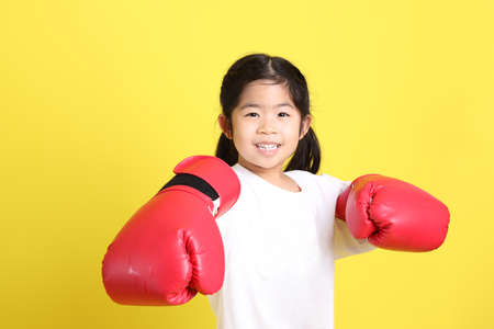 The little Asian girl with casual clothes playing on the yellow background.の写真素材