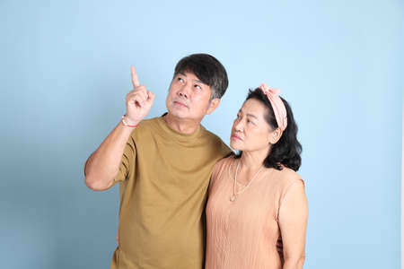The cute senior Asian couple with casual clothes standing on the blue background.の写真素材