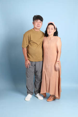 The cute senior Asian couple with casual clothes standing on the blue background.の写真素材